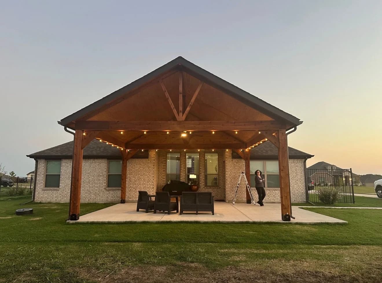 Completed cedar pergola with café lighting over backyard patio in Forney.