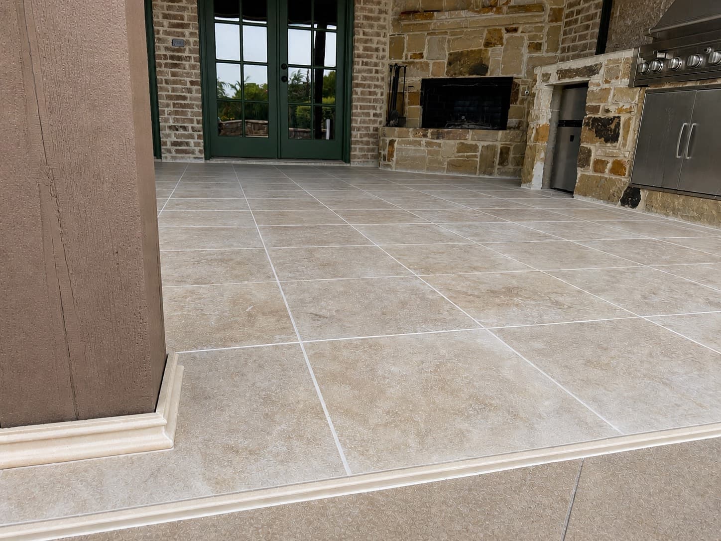 Close-up of finished travertine-look porcelain tile and base trim against textured column wrap.