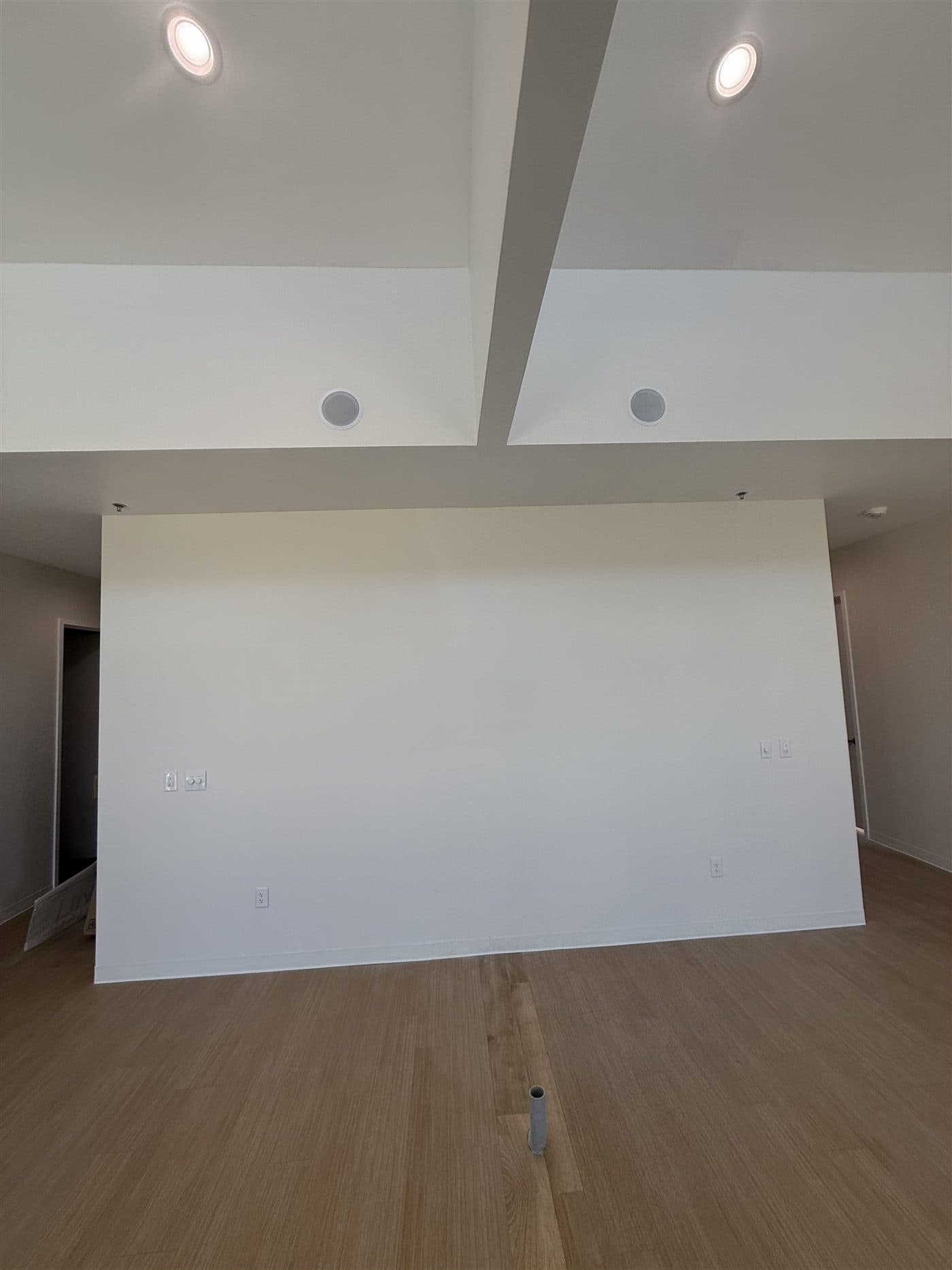The same reception area as a bare white-box shell before build-out: painted drywall, open floor, no desk, no feature wall, and an exposed ceiling grid.