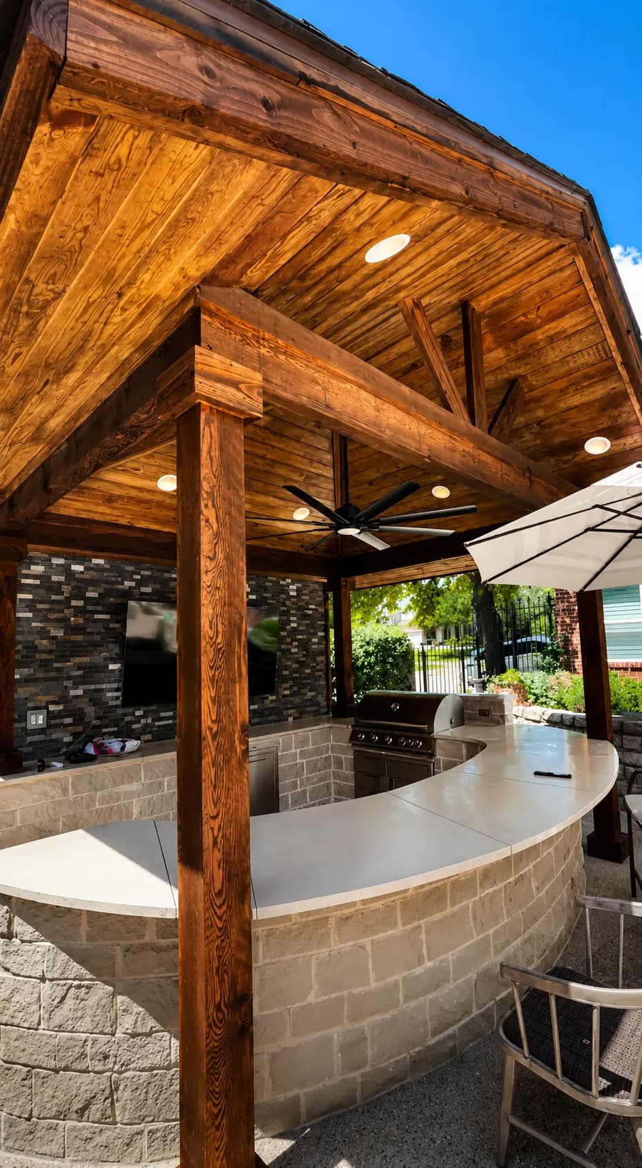 Curved stone outdoor kitchen bar under a cedar pavilion
